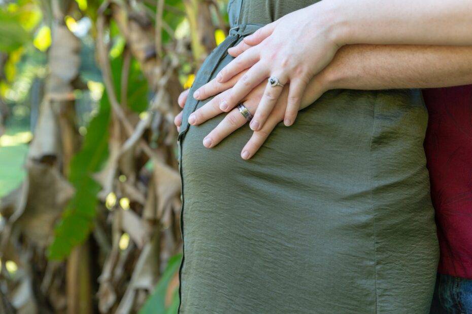 man wraps his arms around pregnant woman tummy